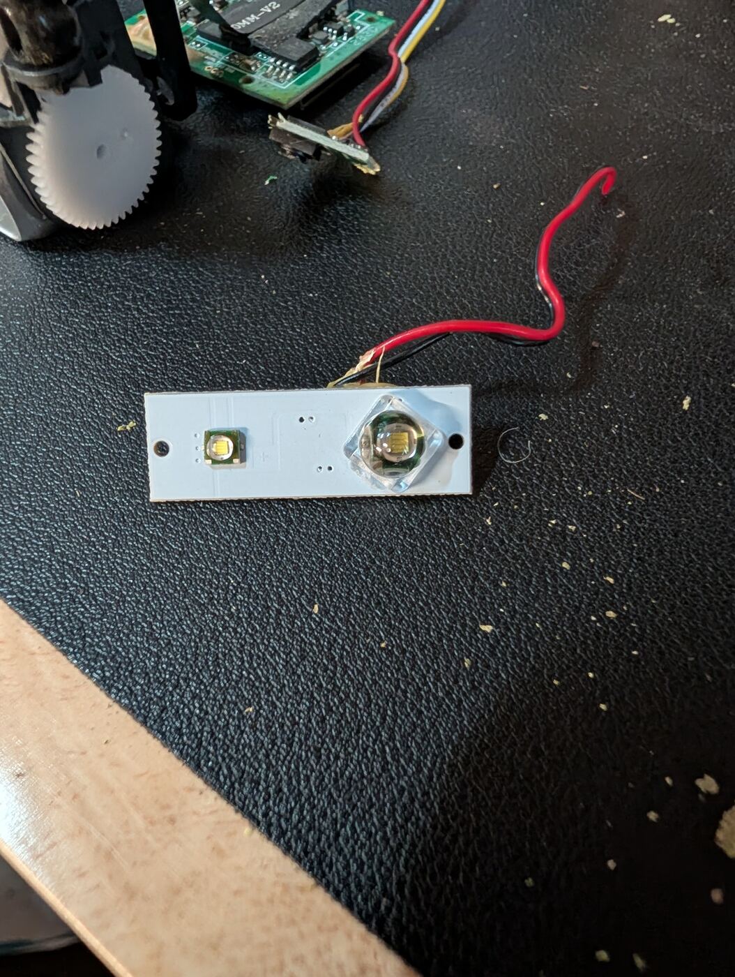 A small dual-LED board salvaged from an old device, with red and black wires